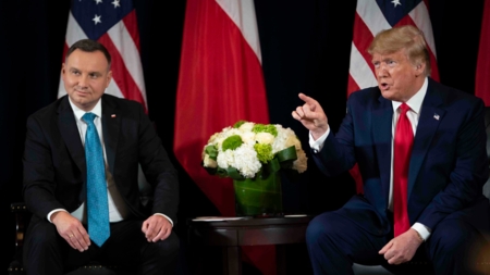 Bildet viser Polens president Andrzej Duda og Donald Trump sittende på en scene foran sine respektive lands flagg i USA i september 2019.