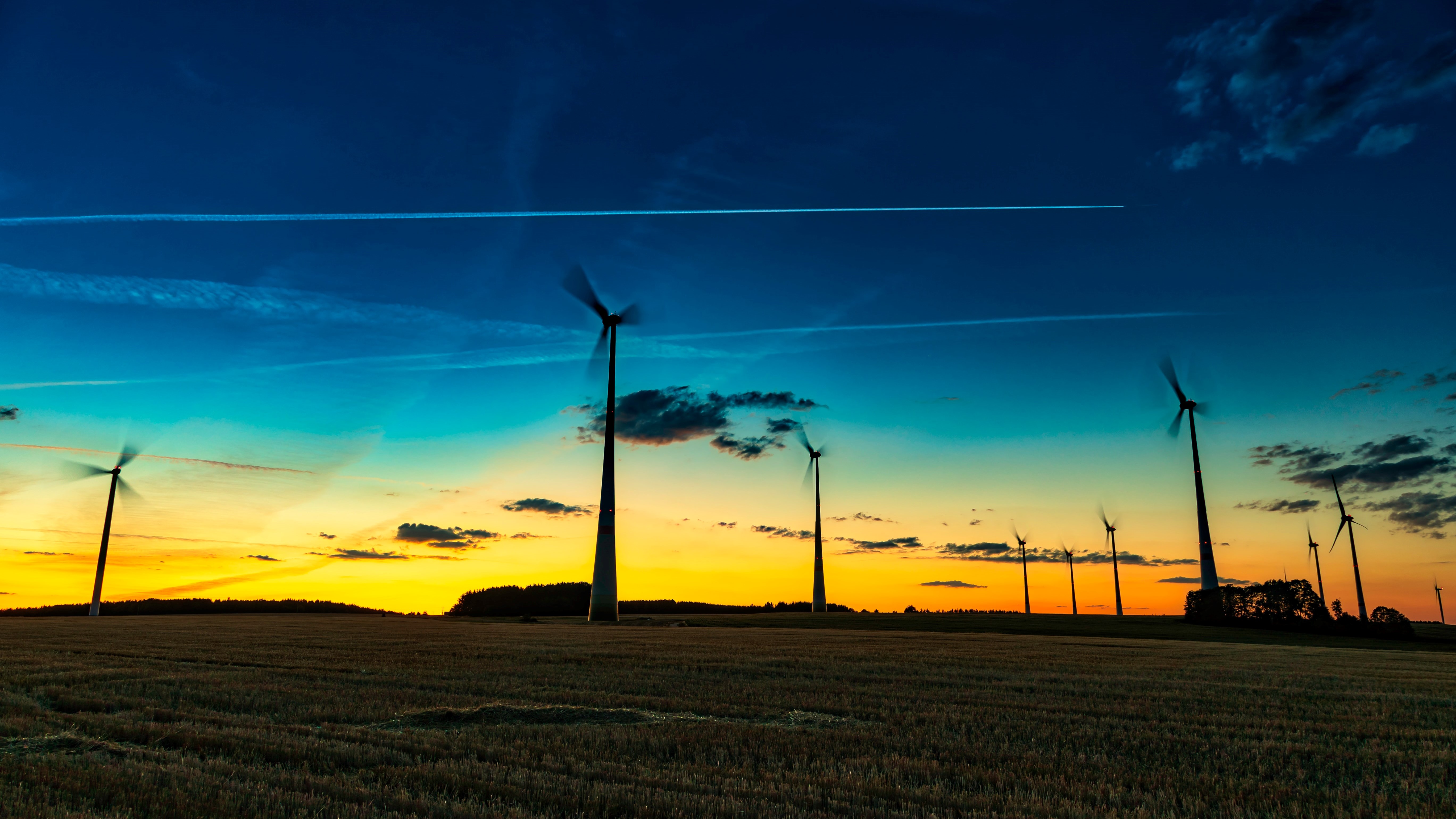 The image shows windmills at sundown